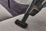 Miele HX-EC 10 Compact Handheld Brush — shown cleaning a sofa cushion